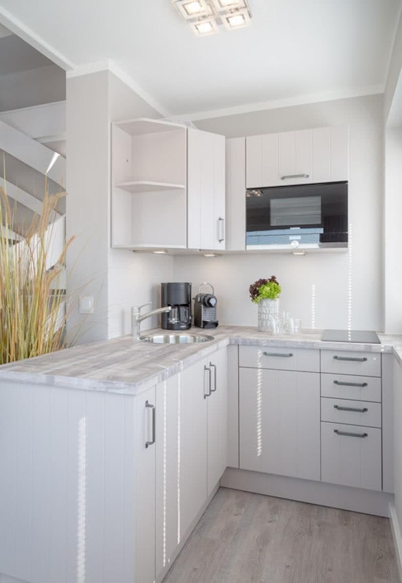 Moderne weiße Küche der Ferienwohnung mit Induktionskochfeld, Spüle, Mikrowelle und Kapselkaffeemaschine